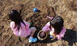 女の子2人が砂場遊びしている